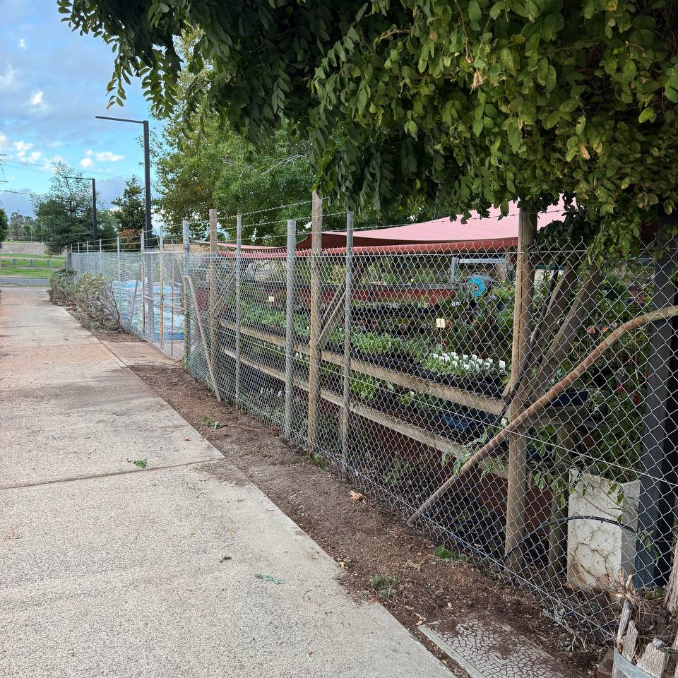 Chain-link security fence with barbed-wire top on timber and steel posts
